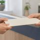 Two people passing a blank requisition folder across a clinic counter