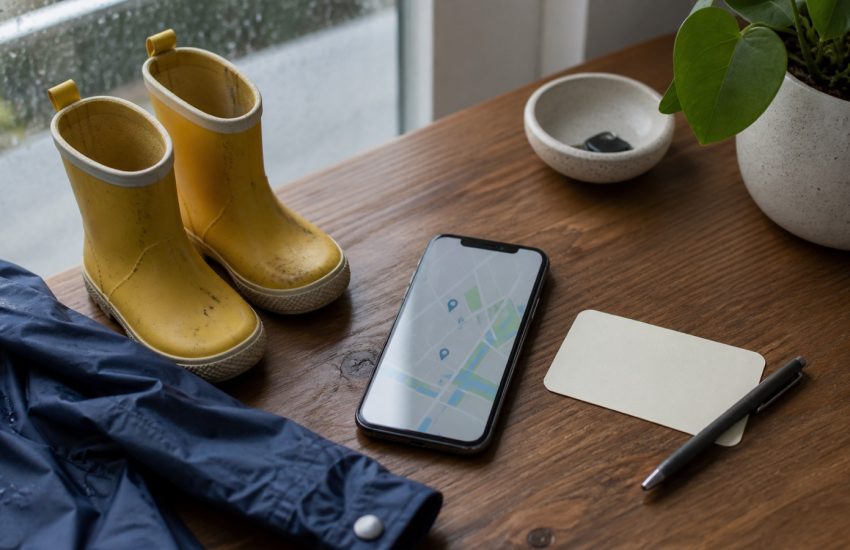 Small rain boots, a phone and a blank appointment card arranged for a Vancouver pediatric care search