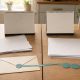 Two blank calendar pads joined across a table seam by an envelope, teal ribbon and three payment markers