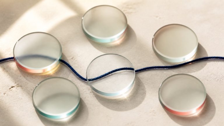 Six frosted glass lenses bringing a navy thread into focus on a warm stone surface