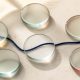 Six frosted glass lenses bringing a navy thread into focus on a warm stone surface