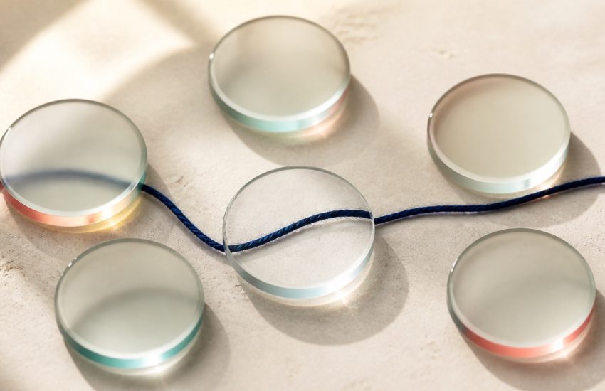 Six frosted glass lenses bringing a navy thread into focus on a warm stone surface