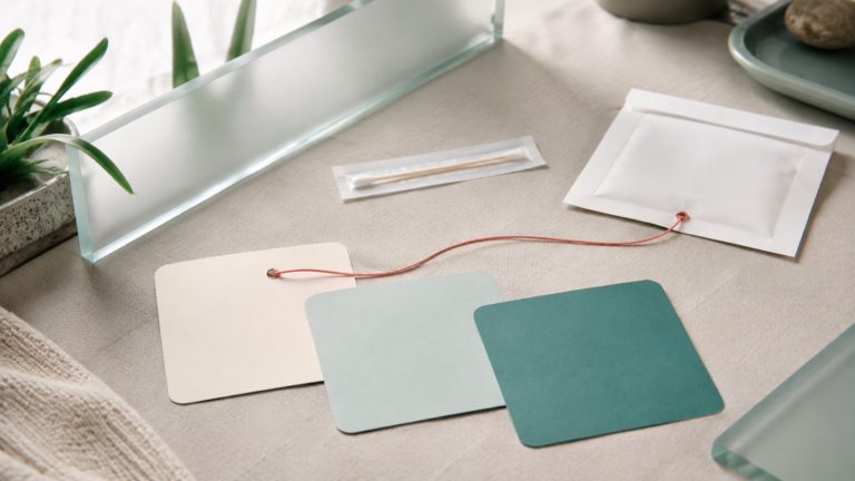 Abstract paper version cards and a sealed screening kit envelope in a calm clinic palette